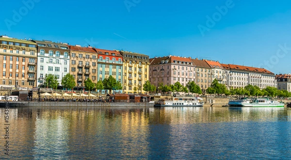 Fototapeta A view from the Vltava river towards colourful buildings on the east bank in Prague in springtime