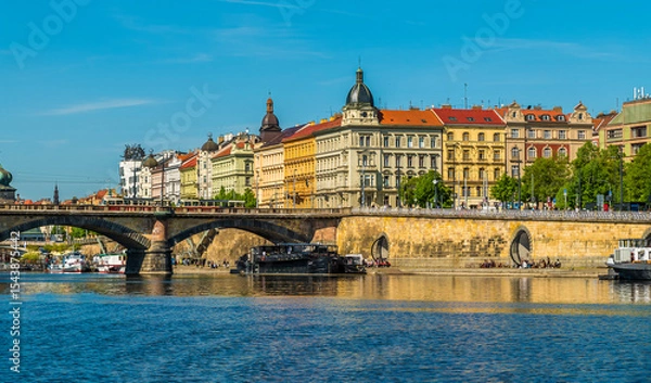 Fototapeta A view from the Vltava river towards river traffic passing under the Palacke bridge in Prague in springtime