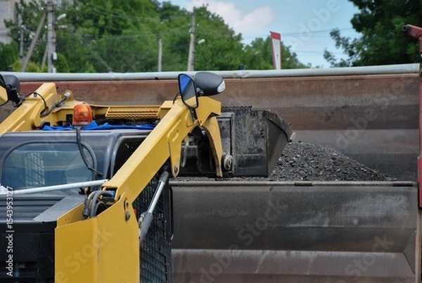 Fototapeta Loading soil with a tractor onto a truck. view of a working excavator