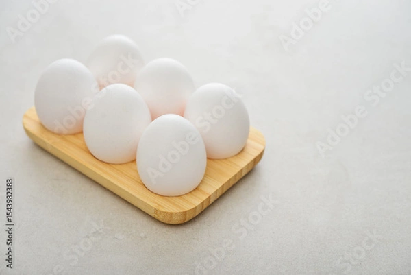 Fototapeta Eggs with white shell in wooden egg holder