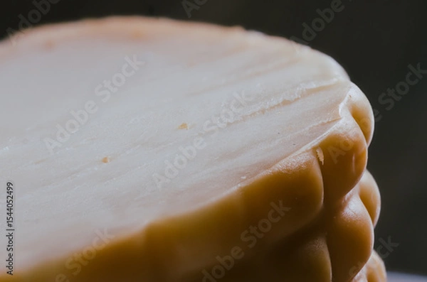 Fototapeta Very detailed macro photo of a sliced piece of textured cheese on a black background