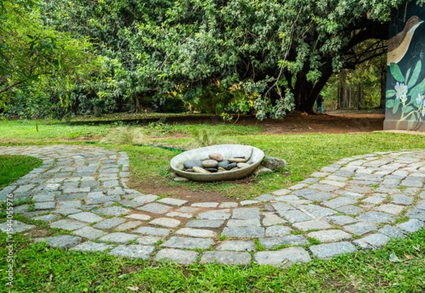 Fototapeta A path with a stone walkway and a small stone bowl