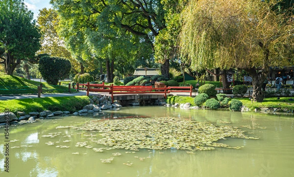 Fototapeta A pond with a red bridge over it