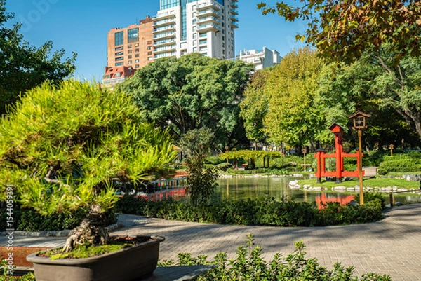 Fototapeta A park with a pond and a red and white statue