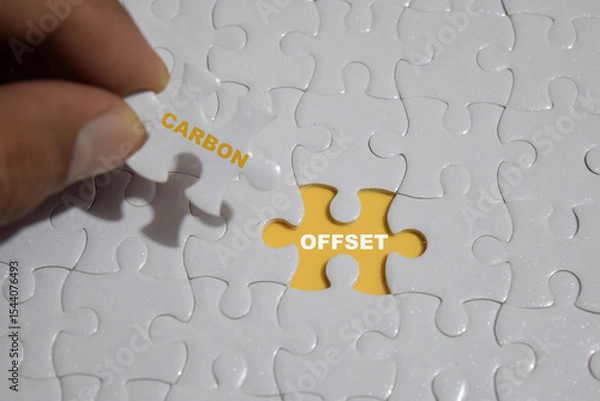 Obraz Hand holding piece of jigsaw puzzle with word carbon and offset.
