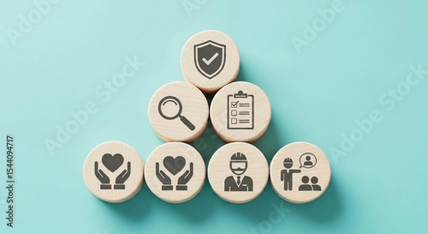 Fototapeta Wooden blocks displaying icons related to safety, health, and employee well being on light blue background