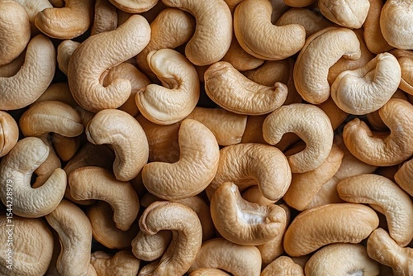 Fototapeta A close-up shot of cashew nuts, showcasing their unique shape and texture. The background is plain to highlight the textured details of each fruit.