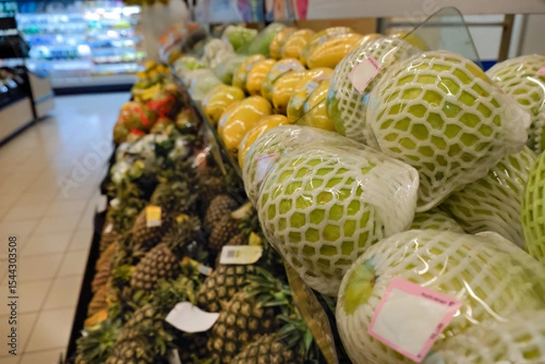 Fototapeta Fresh fruits individually wrapped plastic in produce section, pre-packed. This method to extend shelf life of fresh produce leads to plastic pollution. Plastic waste concept in supermarket.
