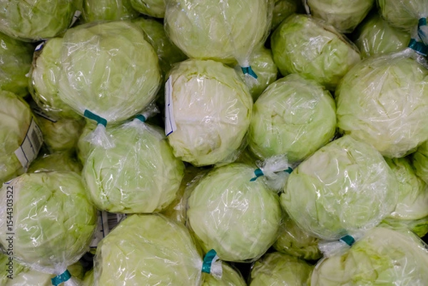 Fototapeta Plastic waste concept in supermarket. Fresh cabbages individually wrapped in produce section, pre-packed in plastic. This method to extend shelf life of fresh produce leads to plastic pollution.