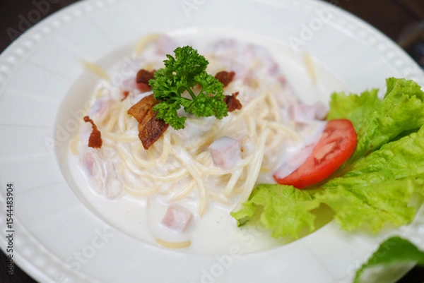 Fototapeta Close up homemade spaghetti carbonara with ham cheese and parsley on white dish. Traditional Italian food