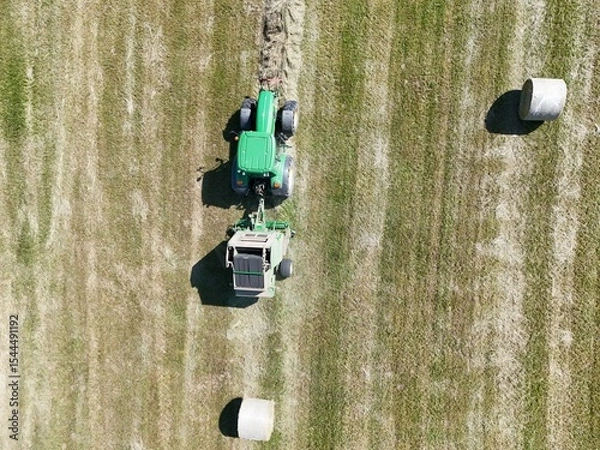 Fototapeta A tractor with a baler in the field, shot with a drone