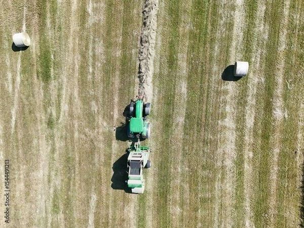 Fototapeta A tractor with a baler in the field, shot with a drone
