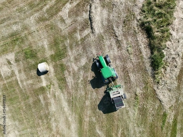 Fototapeta A tractor with a baler in the field, shot with a drone