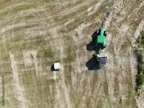 Fototapeta A tractor with a baler in the field, shot with a drone