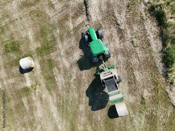 Fototapeta A tractor with a baler in the field, shot with a drone