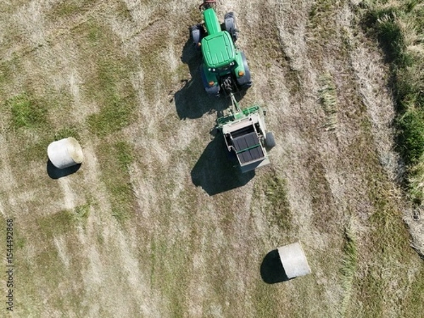 Fototapeta A tractor with a baler in the field, shot with a drone