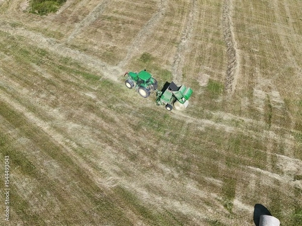 Fototapeta A tractor with a baler in the field, shot with a drone