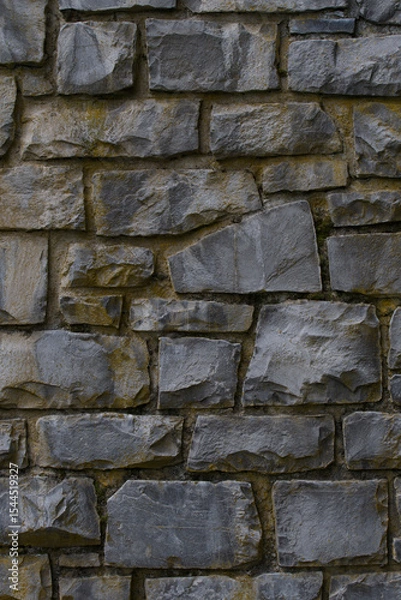 Fototapeta Medieval wall built with dark stone masonry