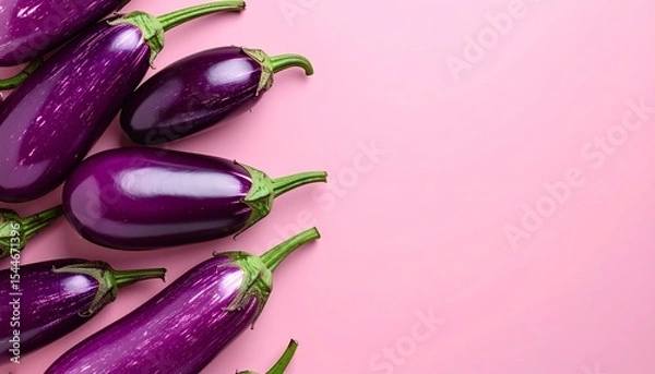 Fototapeta Purple eggplants arranged on the left side of a pink background