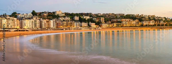 Fototapeta Great panoramic view of La Concha Bay in San Sebastian as the sun sets and the city lights come on