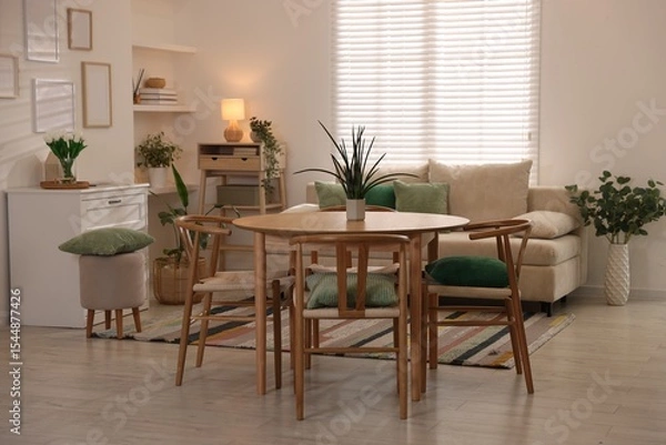 Fototapeta Stylish dining table with chairs and comfortable sofa in room. Interior design