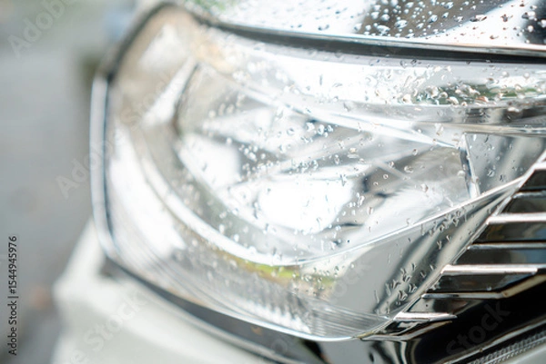 Fototapeta Close-Up Of Vehicle Headlight With Raindrops On A Chrome Surface Under Soft Natural Light