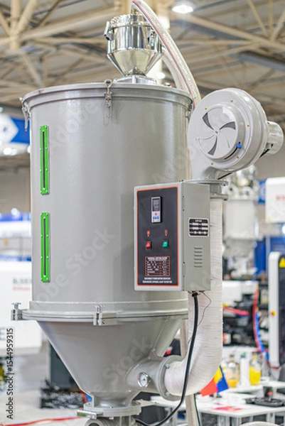Fototapeta Large industrial mixerprocessor with cylindrical base and two silver tanks, indoors in an industrial setting, artificial lighting, no people, metallic hues, blue components, functional style, side v