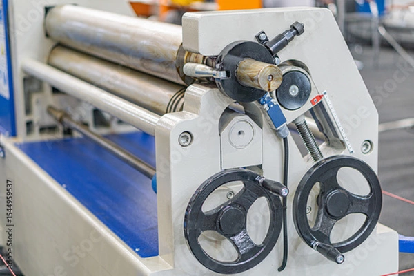 Fototapeta Close-up of a mechanical assembly line cylinder with knobs in an industrial setting, surrounded by other machinery
