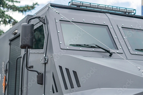 Fototapeta Gray armored personnel carrier APC under overcast skies, angular shape, multiple windows, tinted or protected, antenna, rugged terrain design, side perspective, no visible texts or branding, open a