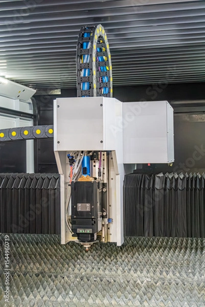 Fototapeta Industrial robotic arm system in an industrial setting, constructed from metal, features blue-tipped joints likely sensors or motors Image is dimly lit, focusing on design and construction without a