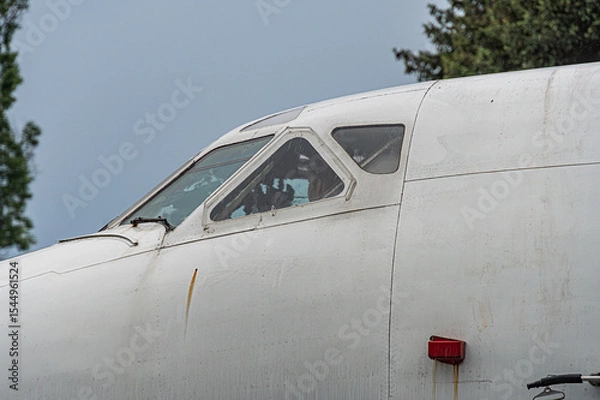 Fototapeta An aged white single-engine aircraft, parked outdoors on an overcast day with open cockpit windows The wing extends to the left and theres a small red anti-collision light at the tip Natural setti