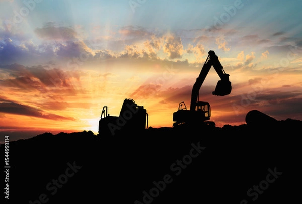 Fototapeta Crawler excavators silhouette are digging the soil in the construction site. on  sunbeam background