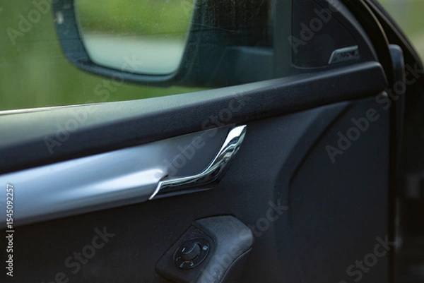 Fototapeta This image features a closeup view of a cars door handle alongside its rear view mirror, showcasing intricate details and craftsmanship