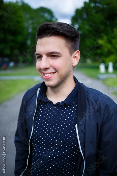 Fototapeta A man in a polka dot shirt and black jacket smiles brightly