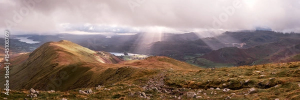 Obraz Panorama of shafts of sunlight breaking thorugh clouds on the descent from Great Rigg on the Fairfield Horseshoe, looking towards Heron Pike, Ambleside and Windermere, Lake District, UK