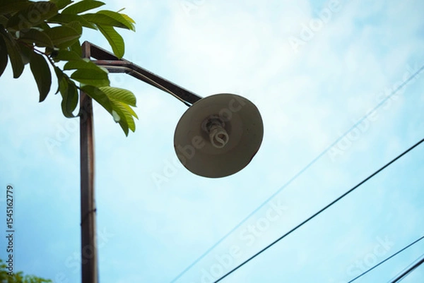 Obraz A lamppost angled upward against a blue sky