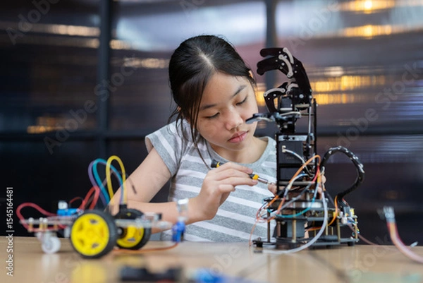 Fototapeta Girl while working Assembly, installation or repair programming robotic arm. Environment features  modern classroom with technology and education tool, enhancing creativity and learning.