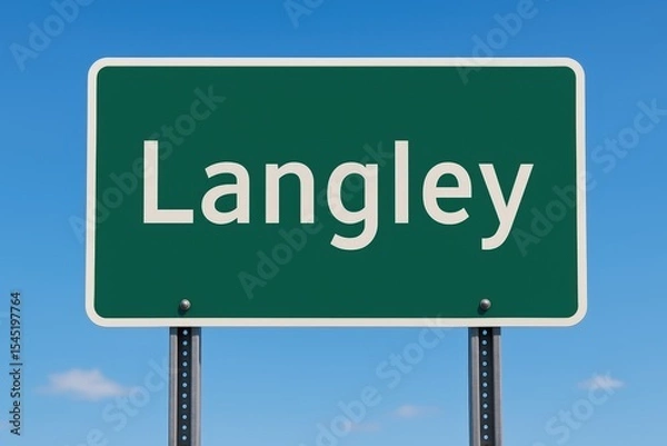 Fototapeta Green road sign displaying "Langley" stands clearly against a bright blue sky, indicating entry or direction to the Canadian city.
