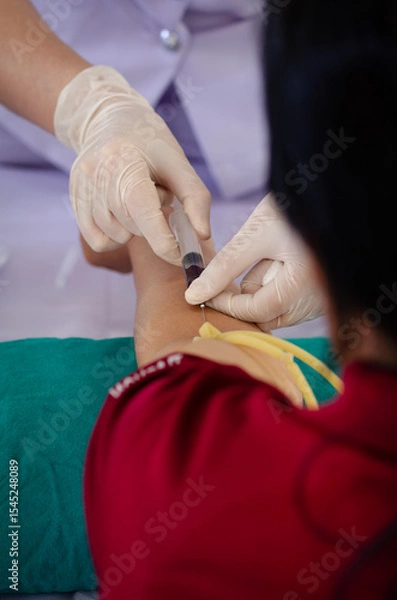 Obraz Soft focus on the hands of the doctor drawing a blood sample from the arm for blood test finds in hospital.