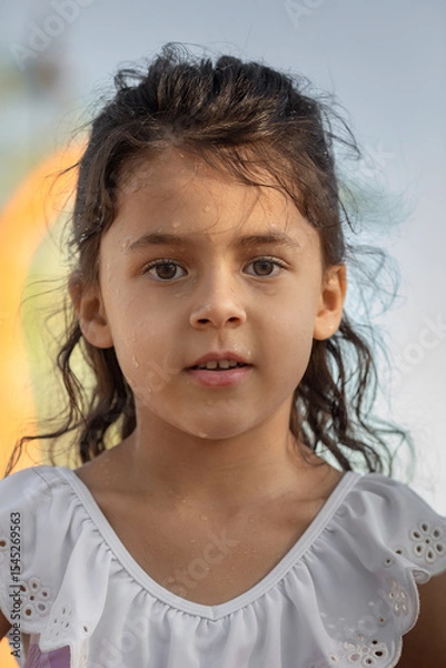Obraz Little girl with wet face standing and looking at camera at sunset time