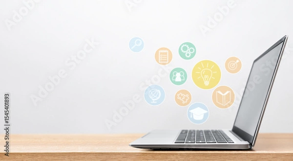 Fototapeta Education themed holograms fly out of a laptop on a table