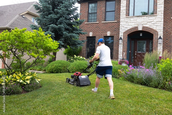 Obraz A teenage boy spends summer days mowing lawns in the neighborhood. With sweat on his brow and steady hands, he cuts neat rows through green grass, building work ethic and pride with every pass. 

