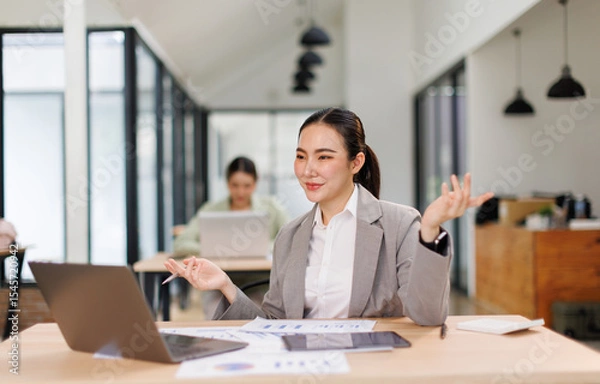 Obraz Asian professional analyst business woman sitting at office desk working on laptop thinking on project plan, analyzing marketing or financial data online, watching elearning webinar.	
