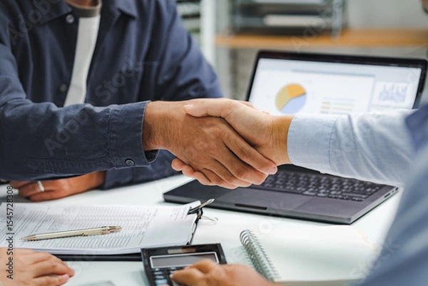 Fototapeta Professional business handshake during financial consultation with advisor, partnership agreement at meeting table with charts and documents