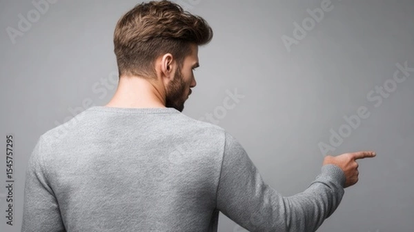 Fototapeta A man in a gray sweater pointing at something