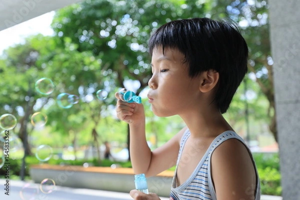 Fototapeta Boy blowing bubbles.