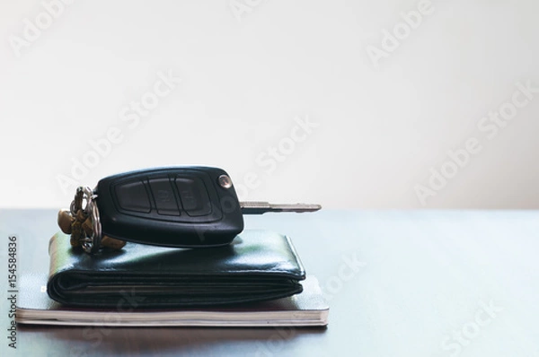 Fototapeta The car key and wallet and passport isolated on the wooded table