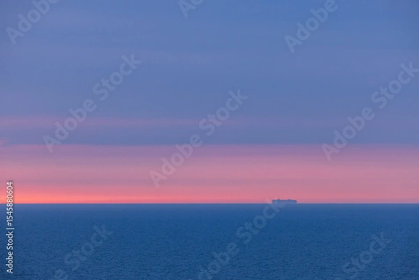 Fototapeta View from a cruise ship in the Norwegian Sea at sunset: the endless horizon glows with soft pink and blue tones. A tranquil ocean and sky background perfect for serene visuals.