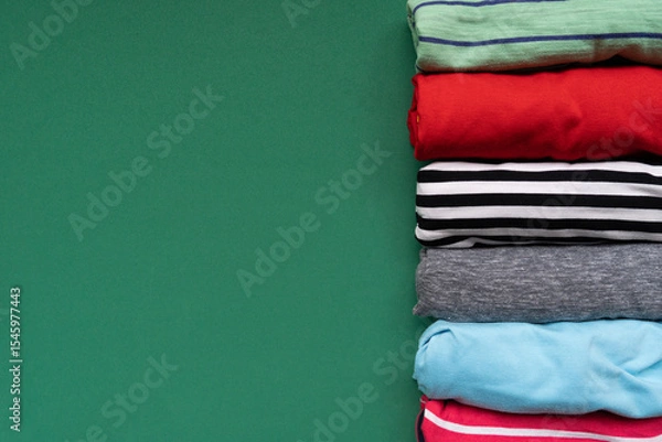 Fototapeta close up of rolled colorful t shirt clothes on green table background, travel and lifestyle concept