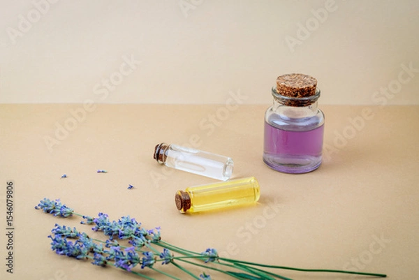 Fototapeta Hydrolat and essential oil bottles with lavender flowers on beige background. Closeup, copy space
